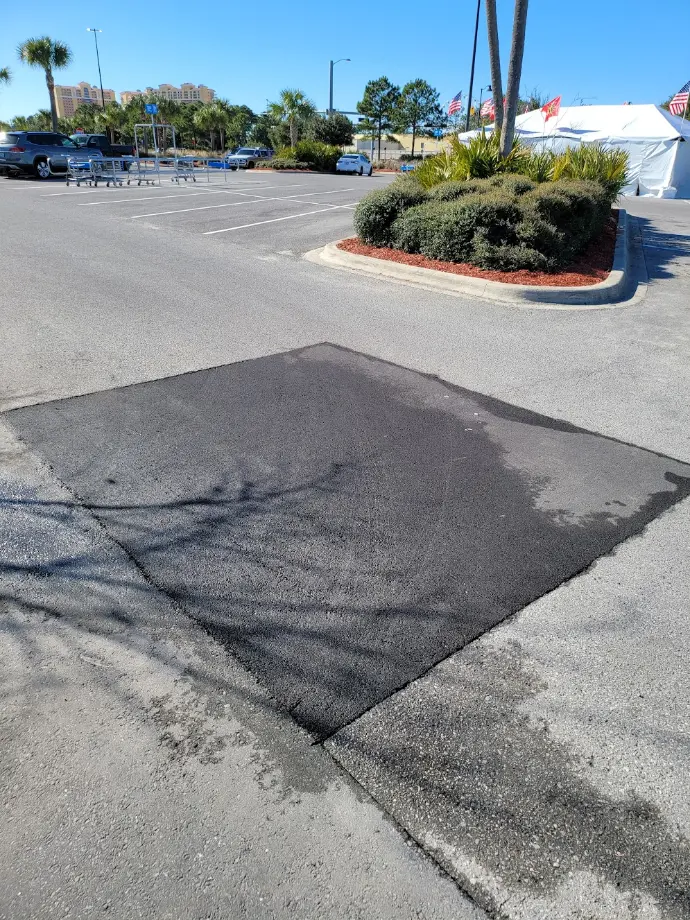 Asphalt patch repair where new pavement meets an existing parking surface